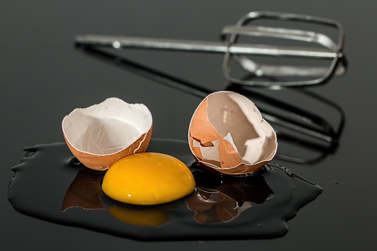 An eggshell broken in half with the raw egg and whisk on a worktop showing how ageing food equipment can damage your process and reputation.