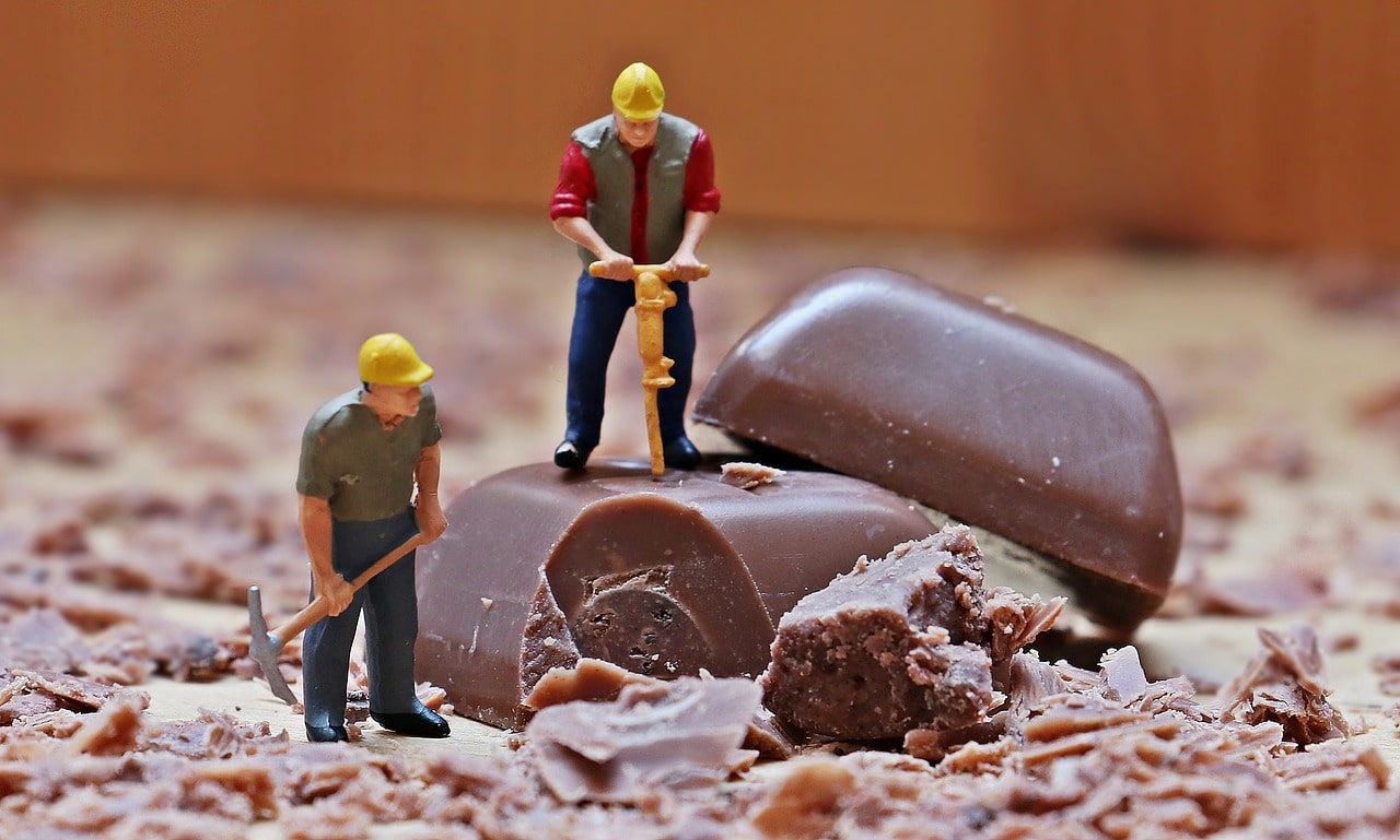 Two builer toy figures using a jackhammer to drill chocolate into shavings.